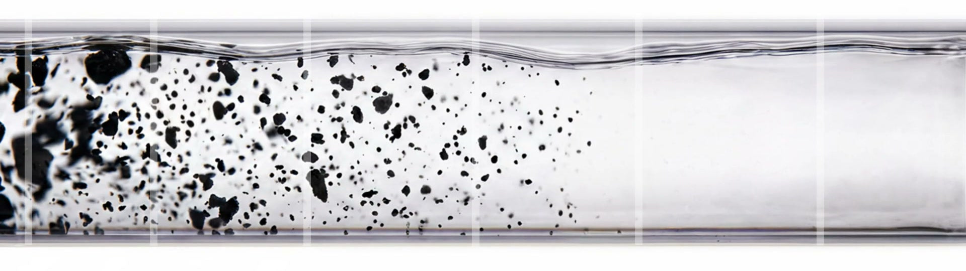 A tube of water, cloudy with particles on the left and crystal clear on the right